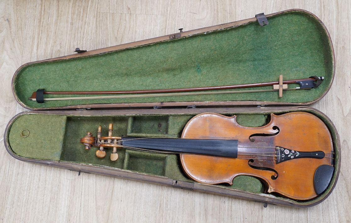 A late 19th century German violin, bearing a Stradivarius label, dated 1717, with mother of pearl inlaid tailpiece, in a walnut case and with bow, the bow stamped Vuillaume & Paris. Condition - fair